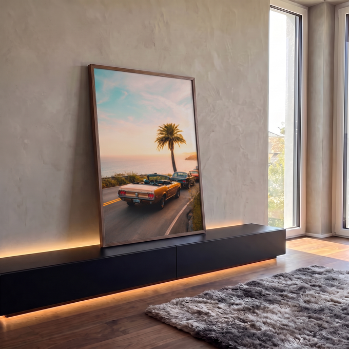 Carro conversível vintage dourado em estrada litorânea ao pôr do sol com palmeira e mar, quadro decorativo