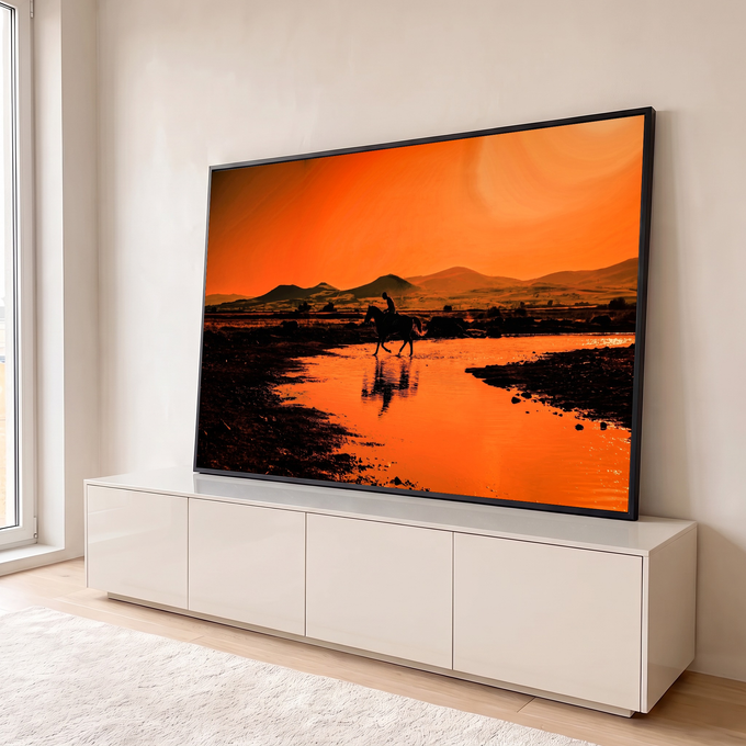 Silhueta de cavaleiro cruzando rio com reflexo na água, montanhas e céu laranja ao pôr do sol, quadro decorativo