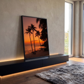 Coqueiros em silhueta na praia tropical com caiaques na areia e céu laranja ao pôr do sol, quadro decorativo