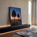 Lua cheia entre duas árvores, estrada de terra e campo dourado sob céu azul e laranja, quadro decorativo