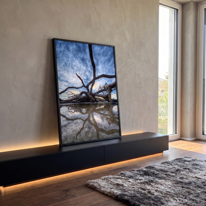 Árvore seca retorcida na praia refletida em poça d'água sob céu azul com nuvens, quadro decorativo