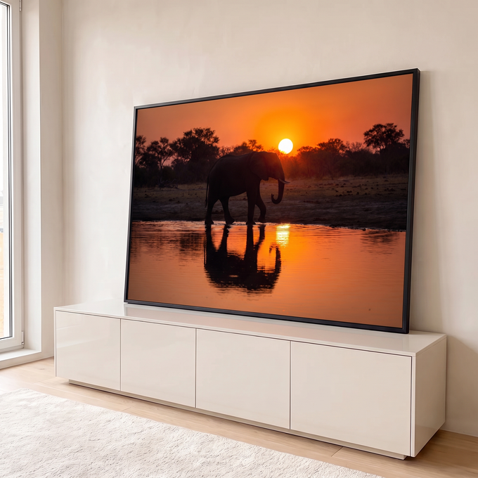 Elefante em silhueta caminhando à beira do lago com reflexo ao pôr do sol laranja, quadro decorativo