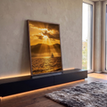 Quadro Decorativo Grande Veleiro ao Entardecer para Sala | quadros decorativos para sala | veleiro no mar dourado sob raios de sol entre nuvens e montanhas ao entardecer | em Quadros para Sala | Porao dos Quadros