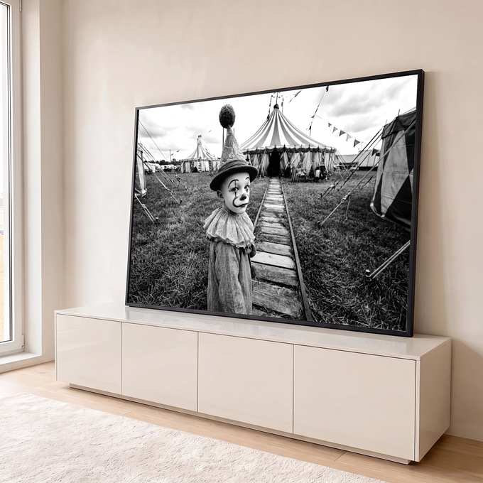 Menino vestido de palhaço com chapéu de pompom diante de tenda de circo em preto e branco, quadro decorativo