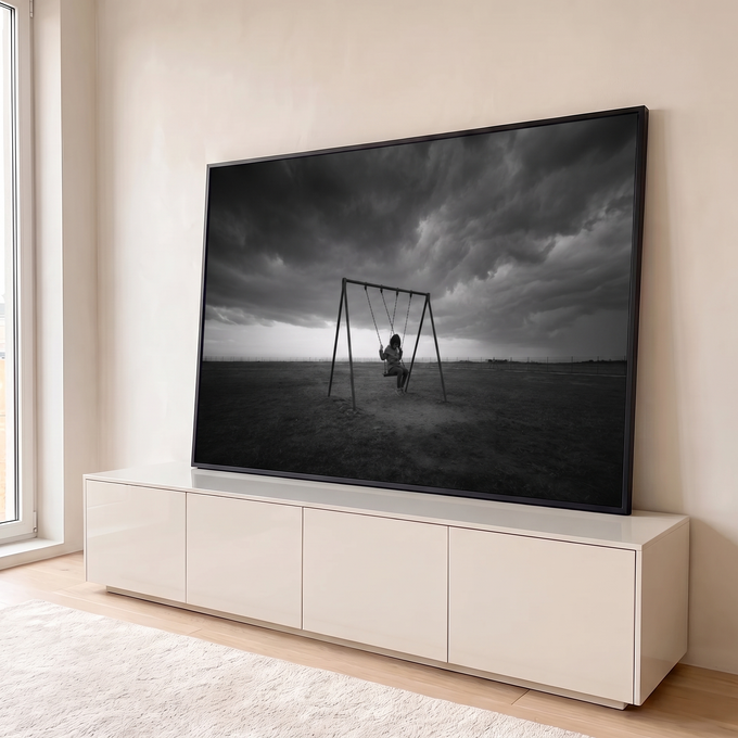 Menina sozinha num balanço em campo aberto sob nuvens de tempestade, foto preto e branco, quadro decorativo