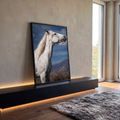 Cavalo tordilho branco de perfil com crina ao vento, céu azul e montanhas ao fundo, quadro decorativo