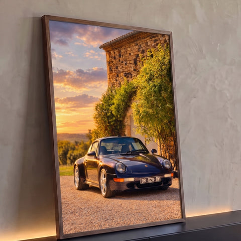 Porsche 911 azul-marinho estacionado diante de casa de pedra com trepadeiras ao pôr do sol, quadro decorativo