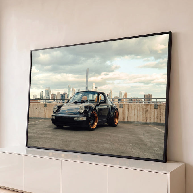 Porsche 911 Targa preto com rodas bronze em terraço urbano e skyline sob céu nublado, quadro decorativo