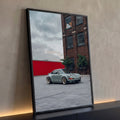 Porsche 911 retrô cinza com rodas bronze em pátio diante de prédio de tijolos, quadro decorativo