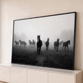 Cavalo negro à frente de uma manada no campo com névoa, em fotografia preto e branco, quadro decorativo
