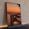 Bicicleta em píer de madeira com lampiões acesos, barcos e mar ao pôr do sol laranja, quadro decorativo