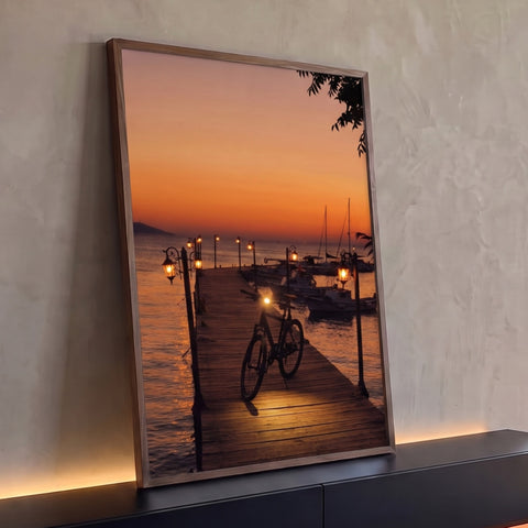 Bicicleta em píer de madeira com lampiões acesos, barcos e mar ao pôr do sol laranja, quadro decorativo