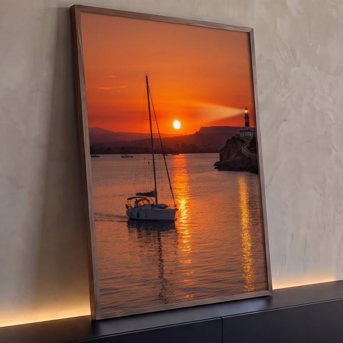 Veleiro navegando no mar laranja ao pôr do sol com farol aceso no penhasco, quadro decorativo