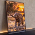 Quadro Decorativo Filhote de Elefante na Água ao Pôr do Sol | quadros decorativos para sala | filhote de elefante espirrando água com a tromba sob pôr do sol dourado | Porao dos Quadros
