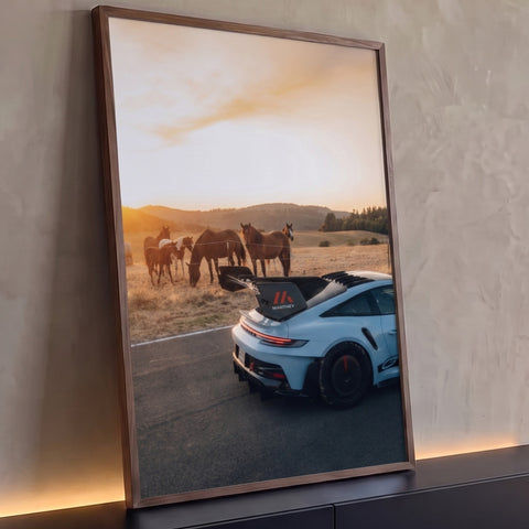 Porsche 911 GT3 RS azul-claro na estrada com cavalos pastando no campo ao pôr do sol, quadro decorativo