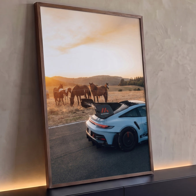 Porsche 911 GT3 RS azul-claro na estrada com cavalos pastando no campo ao pôr do sol, quadro decorativo