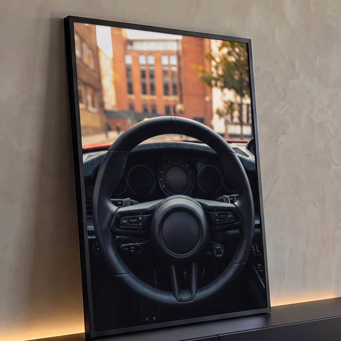 Volante de carro esportivo em couro preto com painel e prédios desfocados ao fundo, quadro decorativo