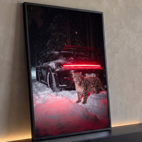 Carro esportivo preto na neve à noite com lanterna vermelha e leopardo das neves à frente, quadro decorativo