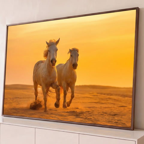 Dois cavalos brancos correndo nas dunas do deserto sob céu laranja do pôr do sol, quadro decorativo