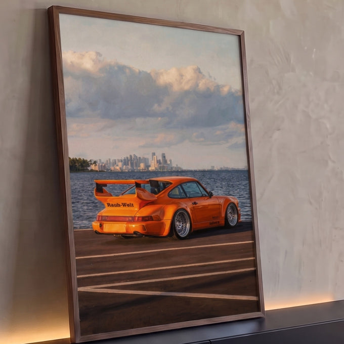 Porsche 911 RWB laranja com aerofólio estacionado à beira-mar, skyline ao fundo, quadro decorativo
