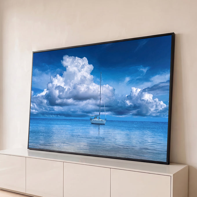 Veleiro branco ancorado em mar azul calmo sob grandes nuvens brancas e céu azul profundo, quadro decorativo