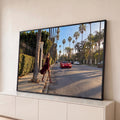 Quadro Decorativo Grande Mulher Vermelho para Sala | quadros decorativos para sala | mulher de vestido bordô caminhando em avenida de palmeiras com carro vermelho ao fundo | Porao dos Quadros