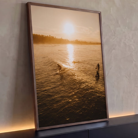 Surfistas em silhueta no mar dourado ao pôr do sol com coqueiros no horizonte, quadro decorativo