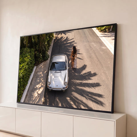 Porsche 911 prateado visto do alto em rua com sombras de palmeiras e mulher de biquíni, quadro decorativo