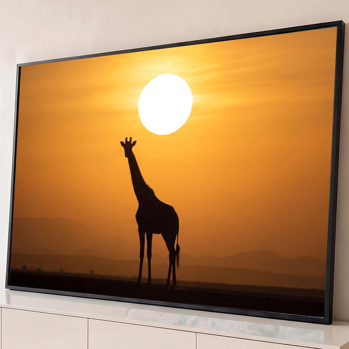 Silhueta de girafa sob sol gigante e céu laranja, com montanhas da savana africana ao fundo, quadro decorativo
