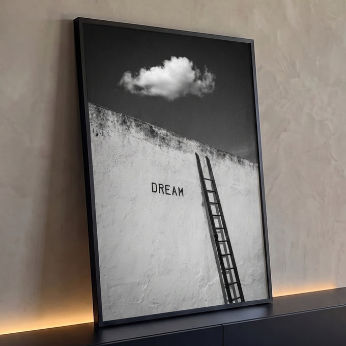 Escada encostada em muro branco com a palavra Dream e nuvem no céu escuro, preto e branco, quadro decorativo