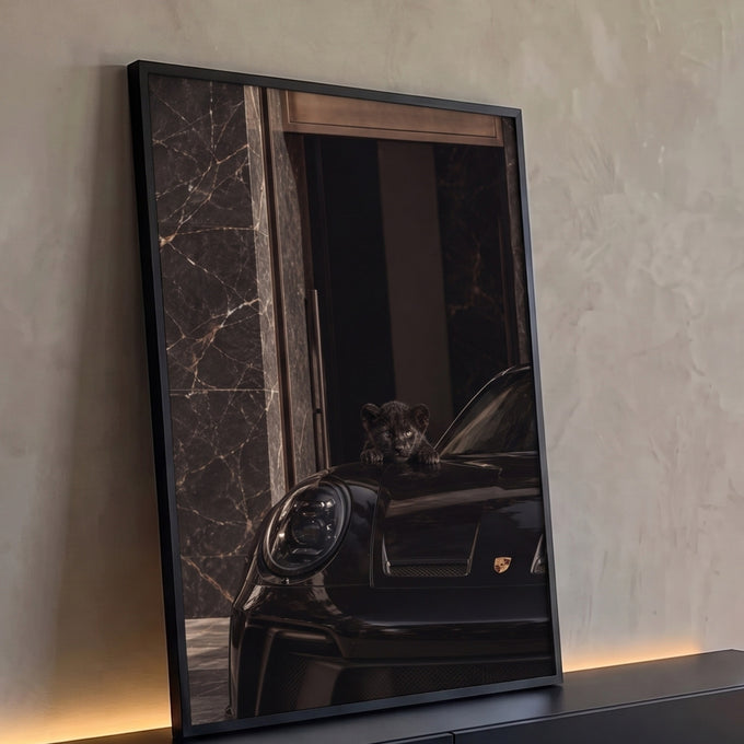 Filhote de pantera negra sobre capô de Porsche preto diante de parede de mármore escuro, quadro decorativo