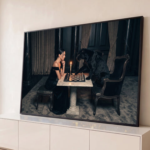 Mulher de vestido preto joga xadrez com pantera negra à luz de vela em salão de mármore, quadro decorativo