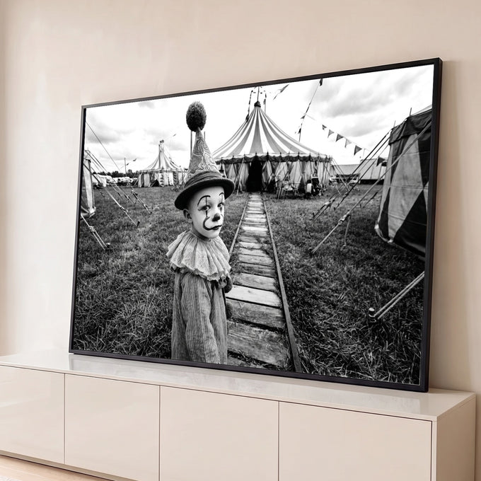 Menino vestido de palhaço com chapéu de pompom diante de tenda de circo em preto e branco, quadro decorativo