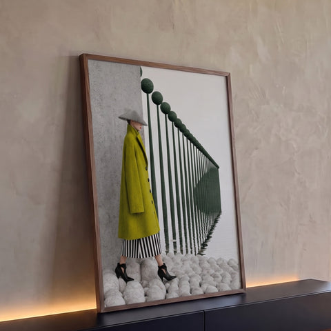Mulher de casaco verde e chapéu cônico diante de postes refletidos na água em neblina, quadro decorativo