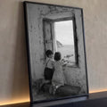 Menino e menina na janela antiga alimentando gaivota diante do mar em preto e branco, quadro decorativo
