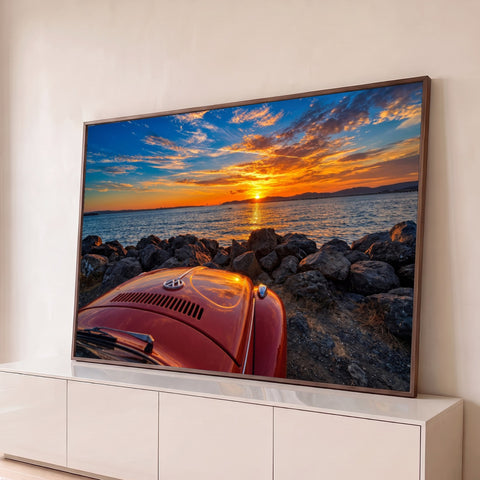 Capô traseiro de fusca vermelho diante de pedras e mar ao pôr do sol laranja, quadro decorativo