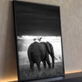 Elefante com duas garças no dorso sob céu escuro e raios de luz em preto e branco, quadro decorativo