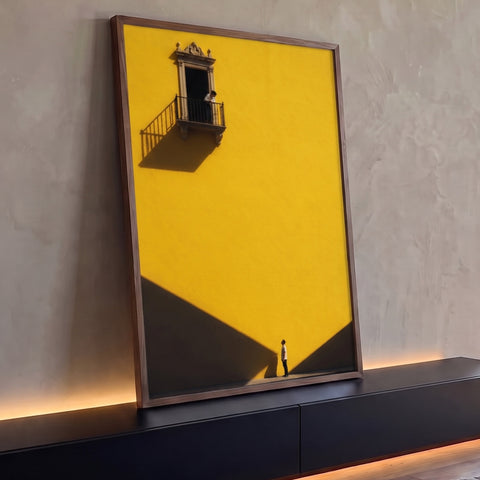 Parede amarela com sacada colonial, pessoa olhando para cima e sombras diagonais, quadro decorativo