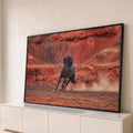 Cavalo negro de crina ao vento galopando levantando poeira em cânion de rochas vermelhas, quadro decorativo
