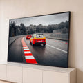Golf GTI de corrida vermelho e amarelo em pista molhada com zebra vermelha e céu nublado, quadro decorativo