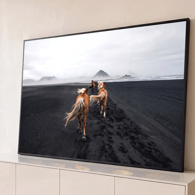 Cavalos de crina loira em praia de areia negra com montanhas na neblina, quadro decorativo
