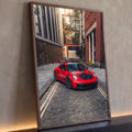 Porsche GT3 RS vermelho com aerofólio em rua de paralelepípedos entre prédios de tijolo, quadro decorativo