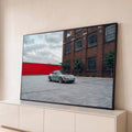 Porsche 911 verde sage em pátio de pedra diante de prédio de tijolos e muro vermelho, quadro decorativo