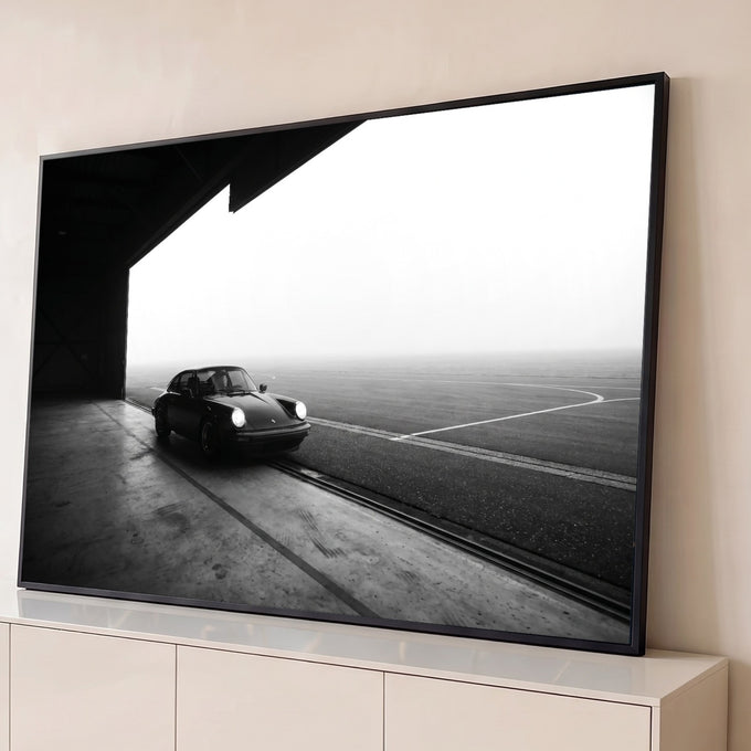 Porsche 911 clássico de faróis acesos saindo de hangar na neblina, foto preto e branco, quadro decorativo