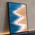 Praia vista do alto com mar azul, espuma branca em zigue-zague e pessoas na areia, quadro decorativo
