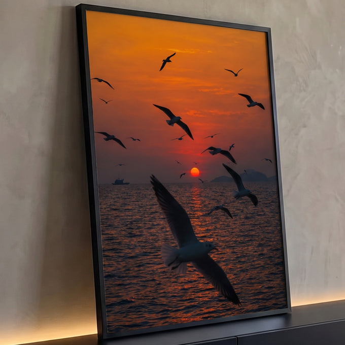 Gaivotas voando sobre o mar com sol vermelho no horizonte e céu laranja, quadro decorativo