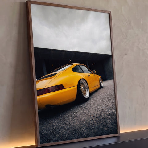 Porsche 911 amarelo rebaixado com rodas douradas sob céu nublado, fotografia vertical, quadro decorativo