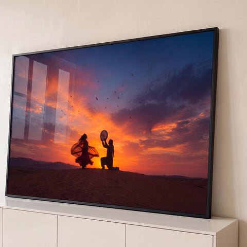 Dançarina e músico com pandeiro em duna ao pôr do sol, céu laranja e pássaros, quadro decorativo