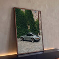 Porsche 911 cinza estacionado em pátio de pedra diante de muro de tijolos coberto de hera, quadro decorativo