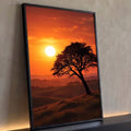 Árvore inclinada em silhueta sobre colinas com sol baixo e céu laranja no pôr do sol, quadro decorativo